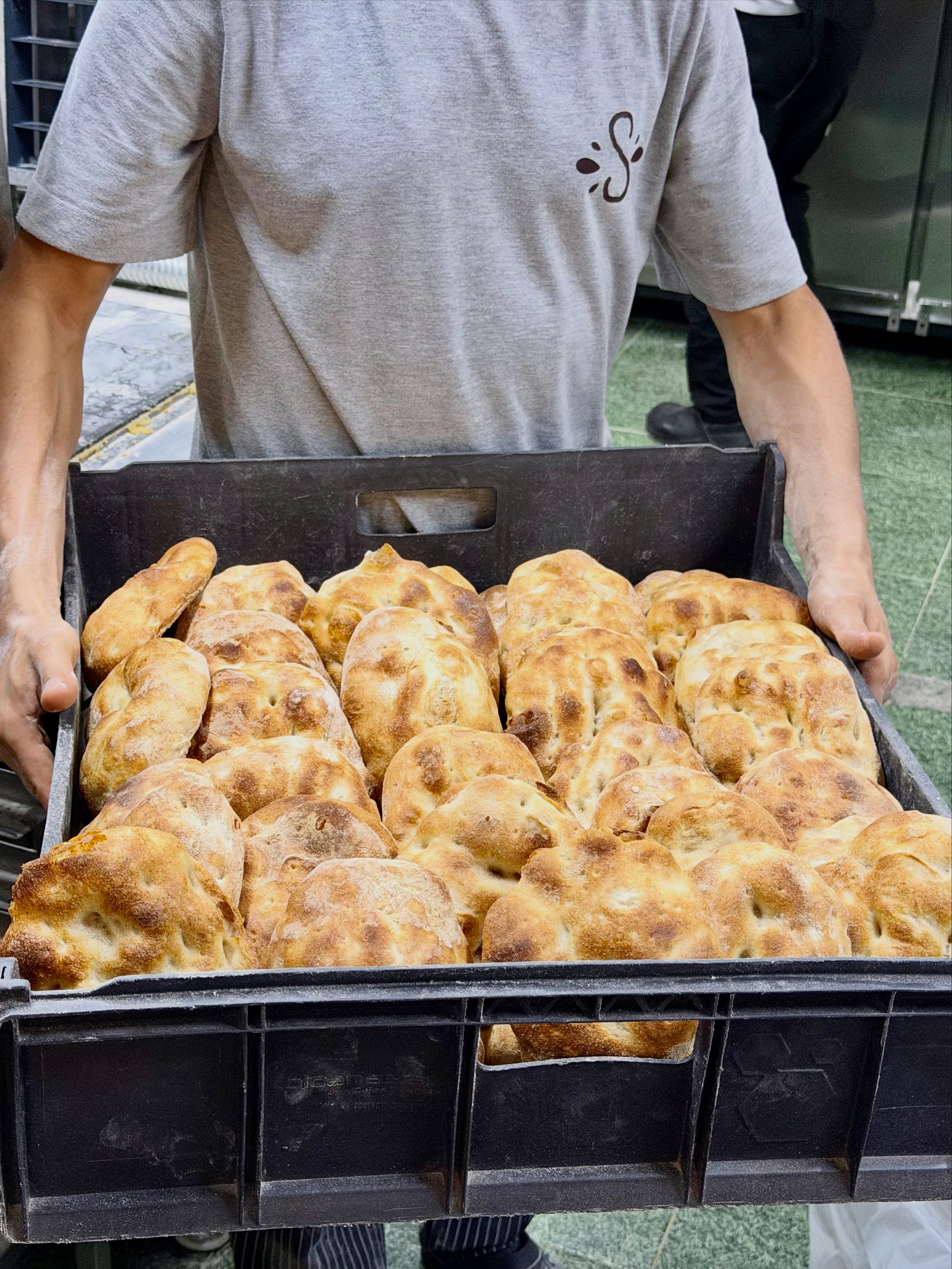 Baker carrying a crate of artisan loaves